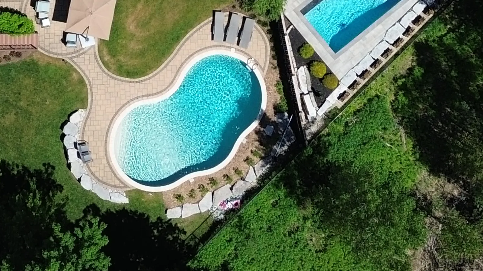 Close aerial view of the kidney-shaped pool and stone patio at 51 Cox Court
