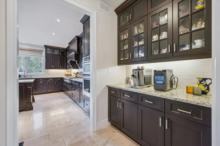 Butler's pantry with glass-front cabinetry, granite counters and coffee station