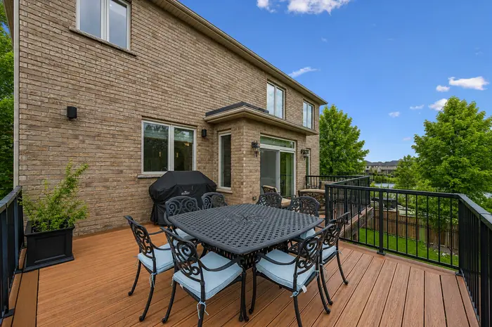 Upper deck with outdoor dining table and barbecue overlooking the pond, digitally enhanced image