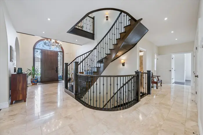 Two-storey foyer with grand curved open staircase and marble floors