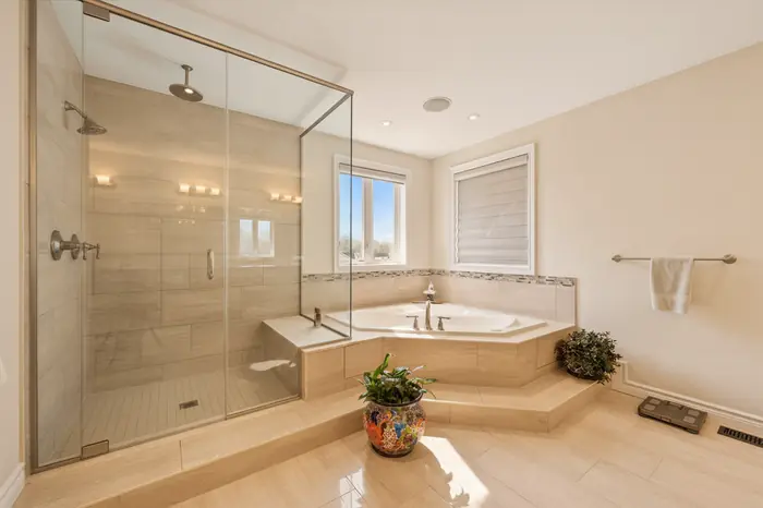 Primary ensuite with glass shower and soaker tub in warm evening light, AI-enhanced image