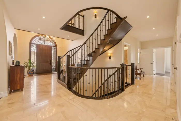 Two-storey foyer and curved staircase bathed in warm golden hour light, AI-enhanced image