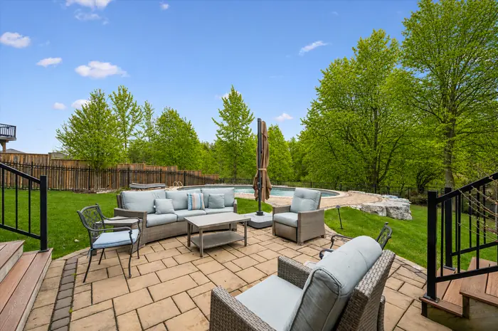 Stone patio with lounge seating beside the pool, digitally enhanced image