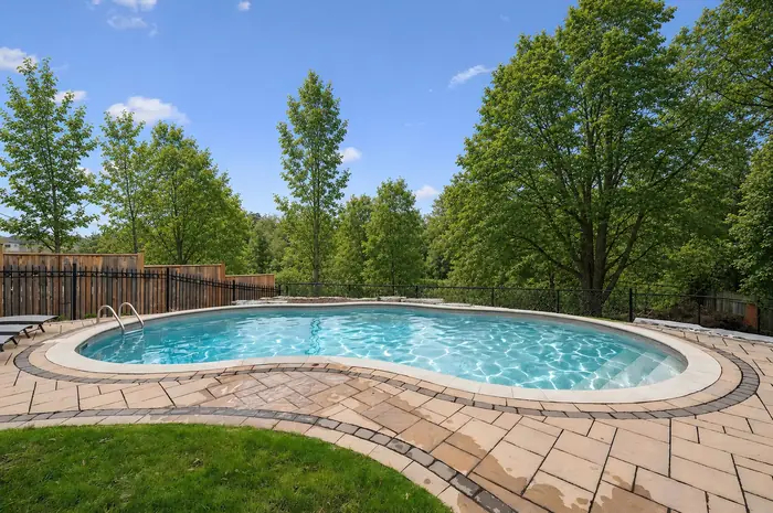 Kidney-shaped pool with stone surround and mature trees, digitally enhanced image