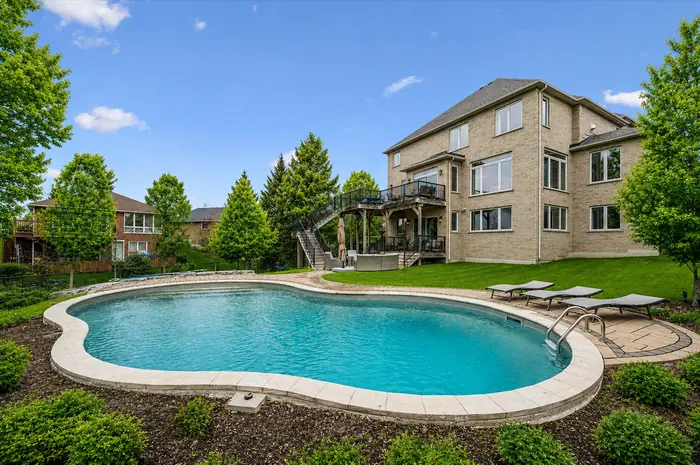 Kidney-shaped pool with the three-storey rear of the home behind, digitally enhanced image