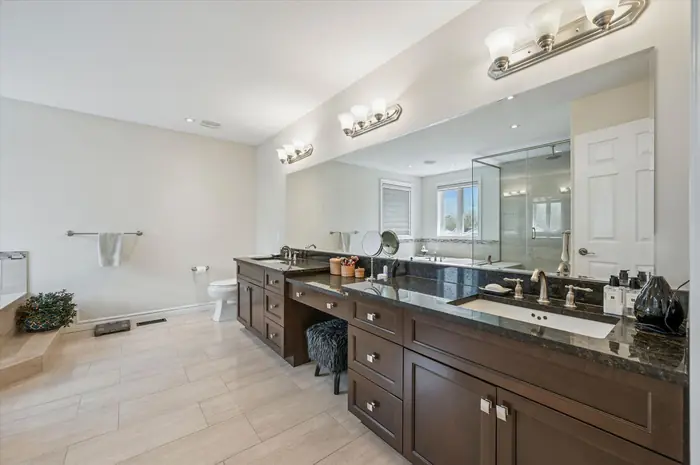 Primary ensuite with double vanity, makeup station, glass shower and soaker tub