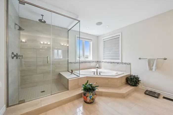 Primary ensuite with rainfall glass shower and corner soaker tub