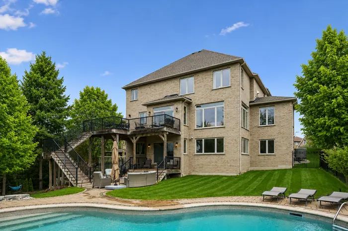 Rear elevation of the home with two-level deck viewed across the pool, digitally enhanced image