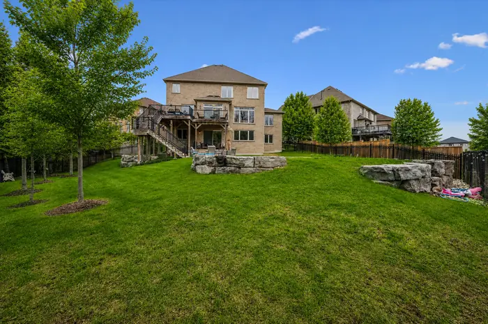 Wide lawn with armour stone landscaping looking back at the rear of the home, digitally enhanced image