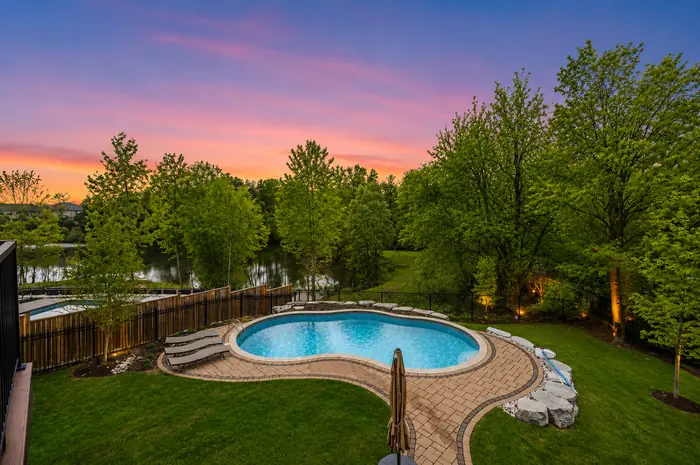 Twilight sky over the pool with landscape lighting and the pond beyond, digitally enhanced image