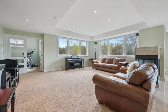 Walkout-level recreation room with gas fireplace, piano corner and greenspace views