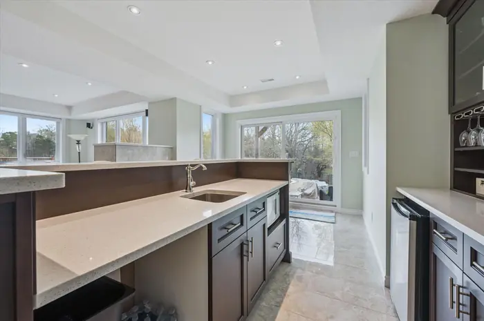 Wet bar with sink and beverage fridge beside sliding walkout to the backyard